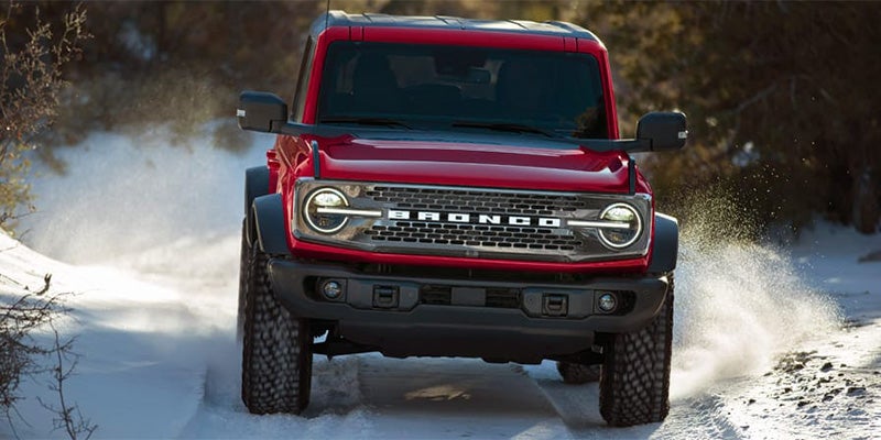 Red off-road ford driving through snow